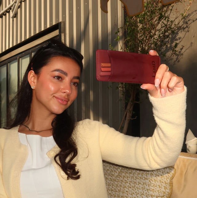 Chica sujetando el estuche guinda mientras se retoca — ginda